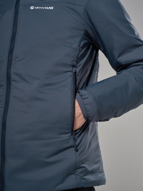 Close-up of a person wearing a Montane jacket in a muted slate blue-gray color, showing the brand logo on the chest and a hand in a zippered pocket.