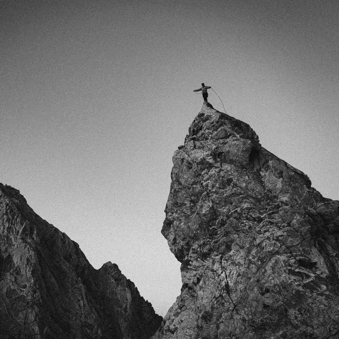 Person standing on a rocky peak with a clear sky