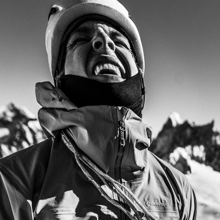 Climber wearing helmet and waterproof jacket in mountain enironment