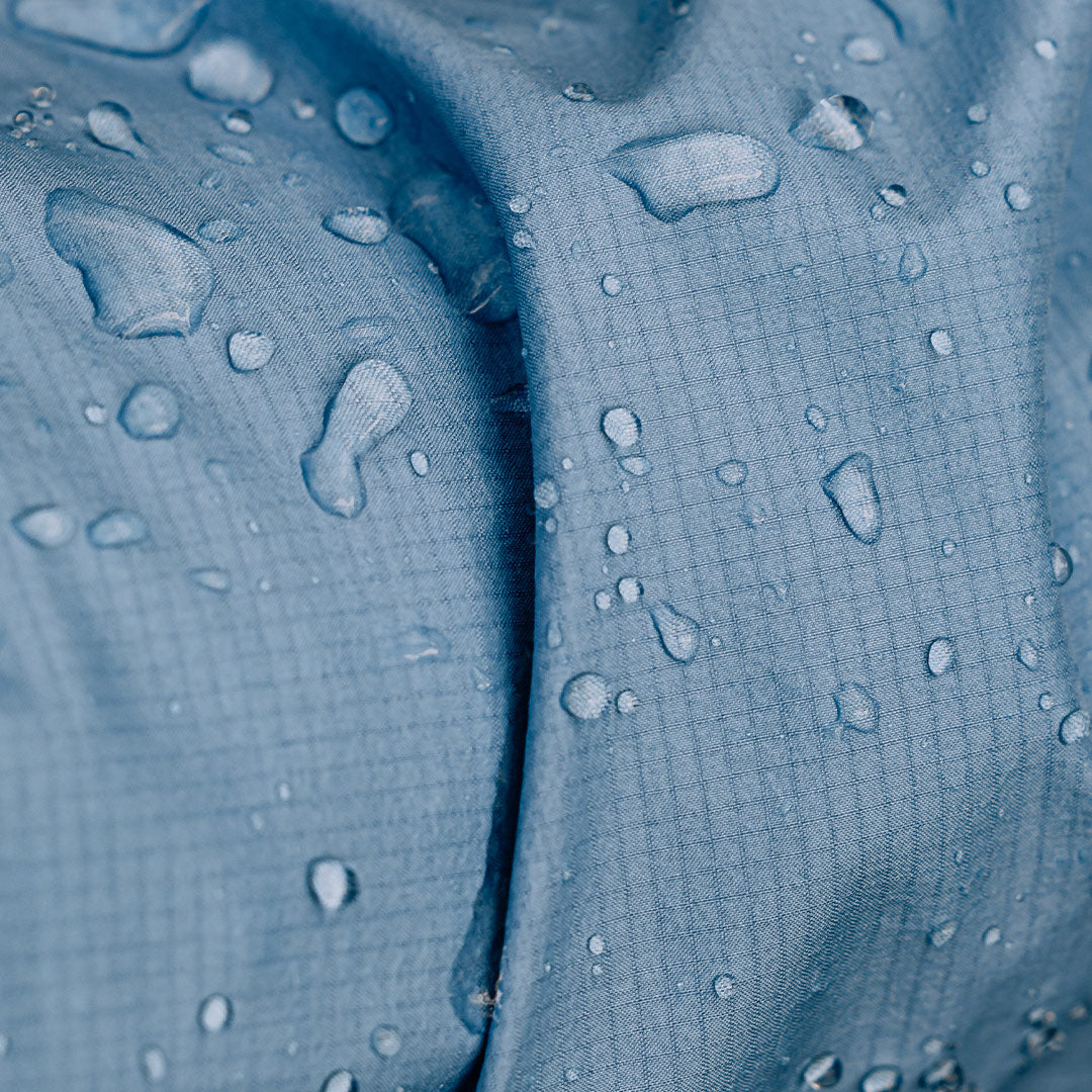 Close up of Montane Cetus Lite Waterproof Jacket in Cornflower with water drops